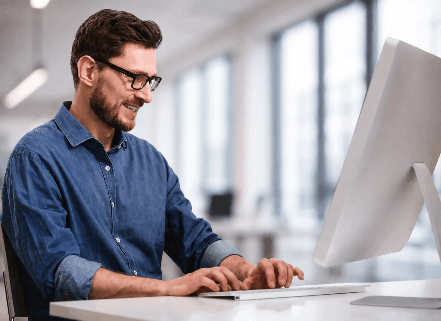 Mann mit Brille und Bart arbeitet am PC
