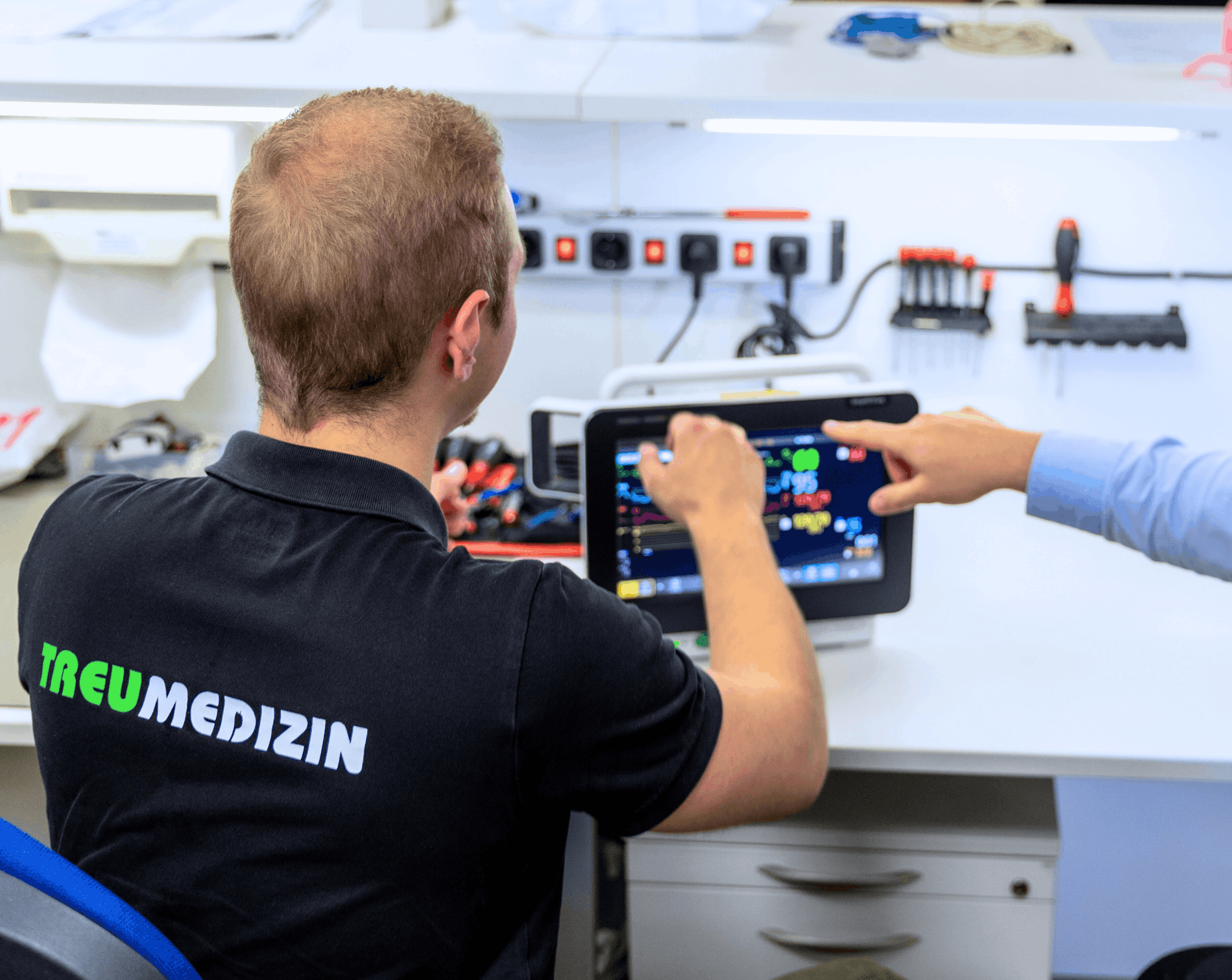 Mitarbeiter von Treumedizin prüfen Gerät und zeigen mit Finger darauf